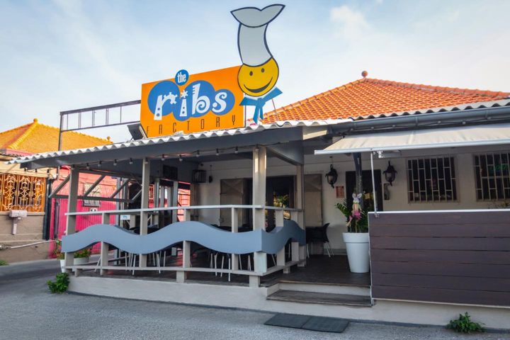 The Ribs Factory storefront with the orange sign and smiling chef